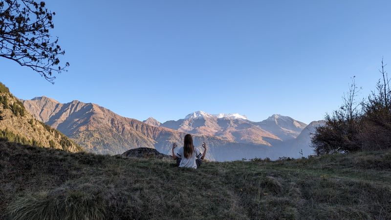 Evi sitzt in den Bergen und blickt auf die Gipfel