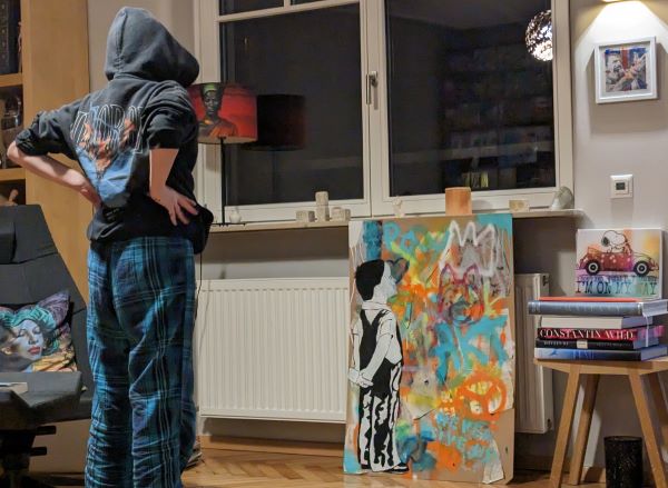Evi vor einem selbstgemalten Werk im Banksy-Stil